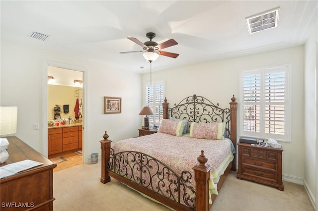 bedroom with a ceiling fan, light colored carpet, visible vents, and ensuite bath