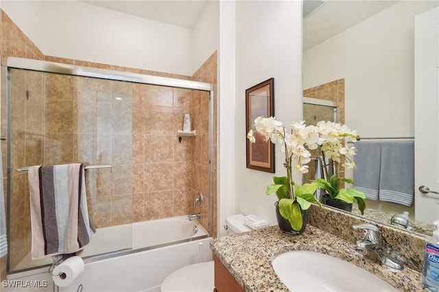 bathroom with visible vents, combined bath / shower with glass door, vanity, and toilet