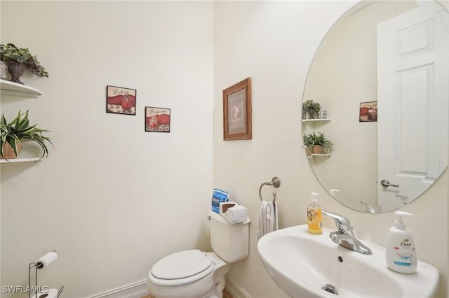 bathroom with a sink, toilet, and baseboards