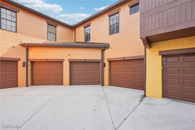 view of front of home featuring a garage, concrete driveway, and stucco siding