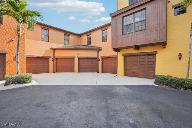 view of property featuring an attached garage, driveway, and stucco siding