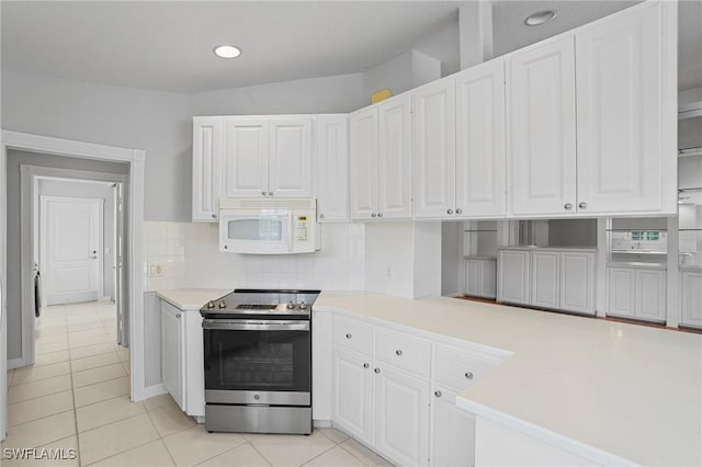 kitchen with white microwave, electric range, white cabinets, light countertops, and decorative backsplash