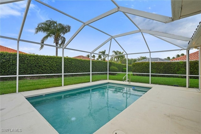 view of pool featuring glass enclosure, a lawn, a patio area, and a fenced in pool