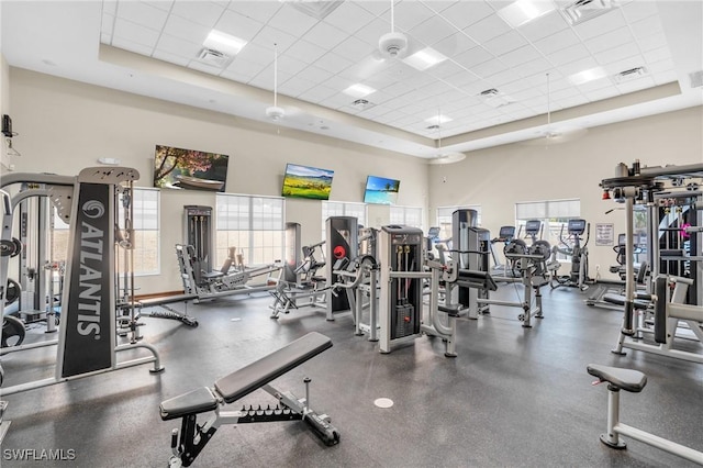 exercise room featuring visible vents, a drop ceiling, a towering ceiling, and a wealth of natural light