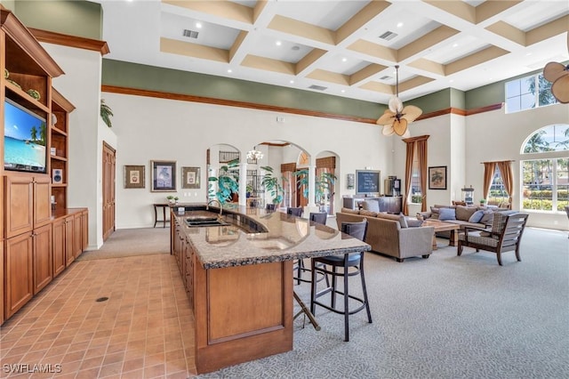 kitchen featuring a high ceiling, a sink, a kitchen breakfast bar, brown cabinets, and open shelves