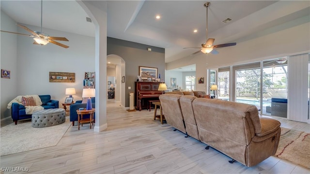 living room with ceiling fan, light wood-type flooring, arched walkways, and visible vents