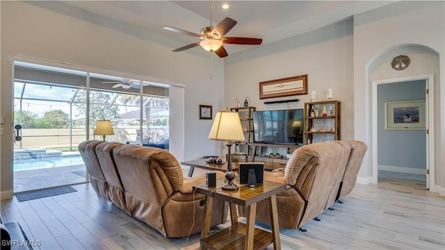 living area with light wood-style floors, ceiling fan, baseboards, and a sunroom