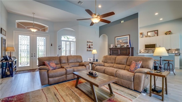 living area featuring arched walkways, french doors, recessed lighting, visible vents, and light wood-style flooring