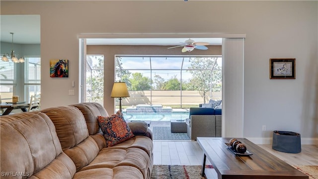 living room with ceiling fan with notable chandelier, wood finished floors, and baseboards