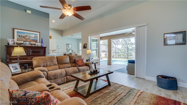 living area featuring a ceiling fan, recessed lighting, baseboards, and light wood finished floors