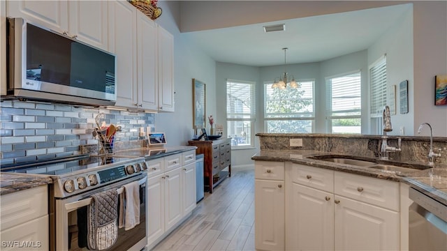 kitchen featuring tasteful backsplash, visible vents, appliances with stainless steel finishes, a sink, and dark stone countertops