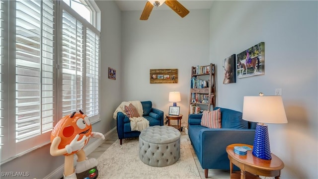 living area featuring wood finished floors, a ceiling fan, and baseboards