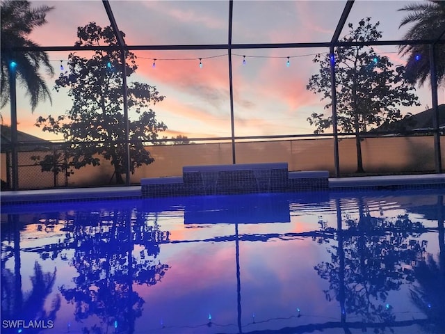 pool at dusk with glass enclosure and an outdoor pool