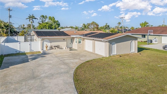 ranch-style home with fence, concrete driveway, a gate, roof mounted solar panels, and a front yard