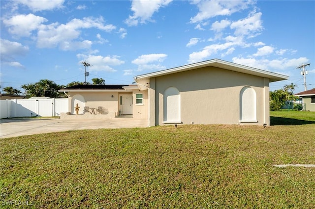 rear view of house with a yard, stucco siding, a gate, roof mounted solar panels, and a patio area