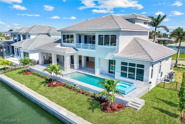 rear view of house featuring a patio, a fenced backyard, a balcony, and an in ground hot tub