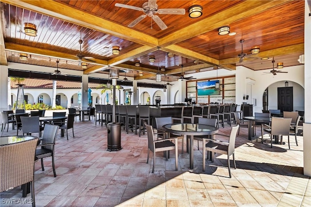 dining space with wooden ceiling, ceiling fan, arched walkways, and beamed ceiling