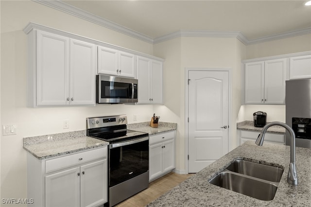 kitchen featuring appliances with stainless steel finishes, a sink, white cabinetry, and crown molding