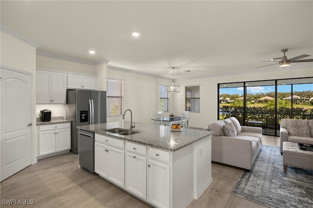 kitchen featuring open floor plan, stainless steel dishwasher, a sink, and light stone countertops