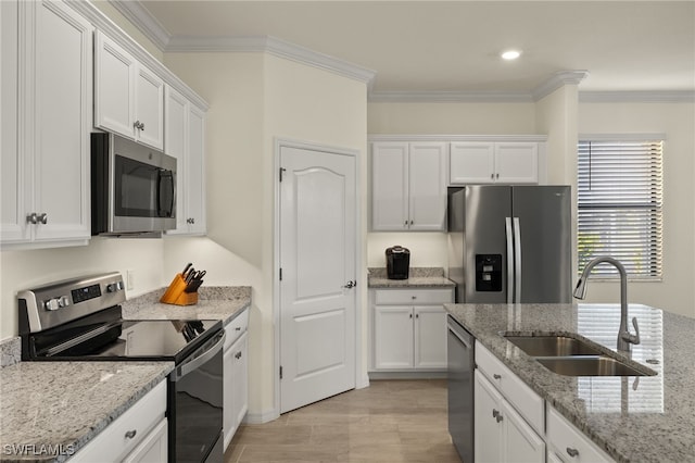 kitchen featuring crown molding, stainless steel appliances, a sink, and white cabinets