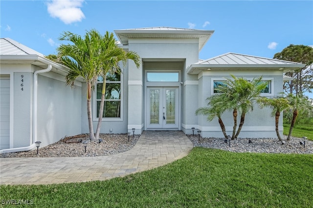 entrance to property with a standing seam roof, stucco siding, metal roof, and french doors