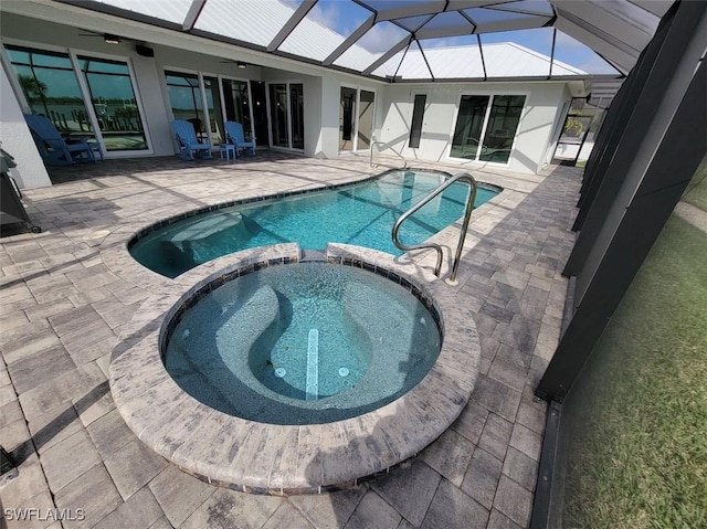 view of swimming pool featuring glass enclosure, a pool with connected hot tub, a patio area, and ceiling fan