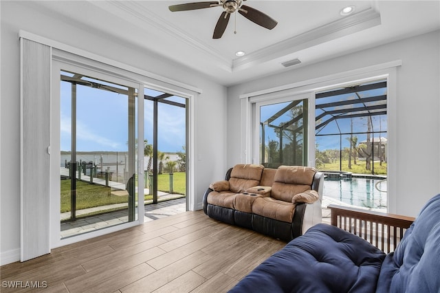 living room with a raised ceiling, visible vents, ornamental molding, a sunroom, and wood finished floors