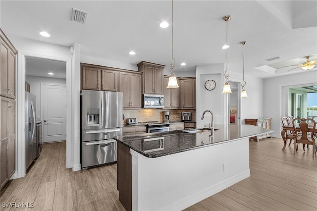 kitchen with appliances with stainless steel finishes, visible vents, a sink, and tasteful backsplash