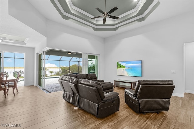 living area featuring ceiling fan, wood finished floors, a sunroom, a tray ceiling, and crown molding