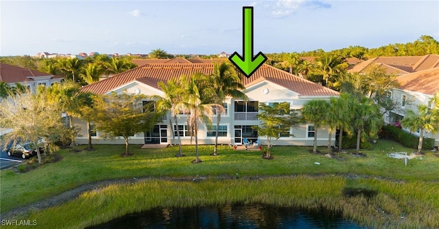 back of house featuring a lawn and a water view