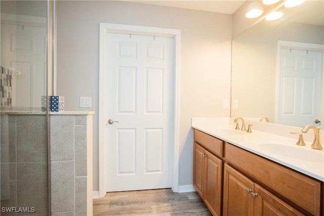 full bathroom with double vanity, wood finished floors, a sink, and baseboards