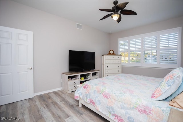 bedroom with ceiling fan, wood finished floors, visible vents, and baseboards