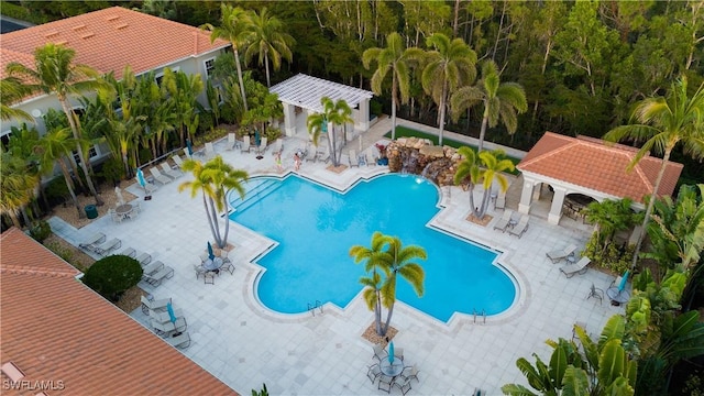 community pool with a patio area, fence, and a gazebo