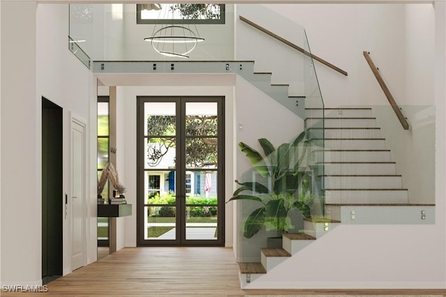 doorway to outside with wood finished floors, french doors, a high ceiling, and stairs