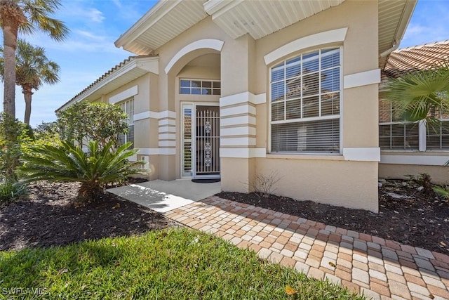 entrance to property featuring stucco siding and a tile roof