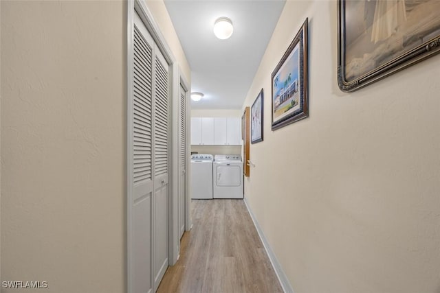 hallway with independent washer and dryer, baseboards, and light wood-style floors