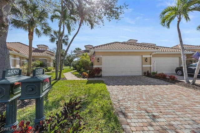 view of front of house featuring an attached garage, stucco siding, a front lawn, a tiled roof, and decorative driveway