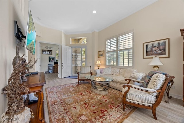 living room with wood finished floors, baseboards, and ornamental molding