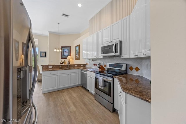 kitchen featuring tasteful backsplash, visible vents, ornamental molding, a peninsula, and stainless steel appliances