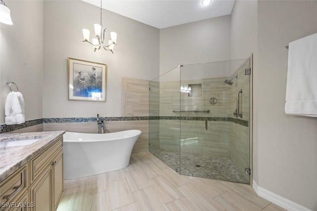 full bathroom with a freestanding tub, vanity, a chandelier, and a shower stall