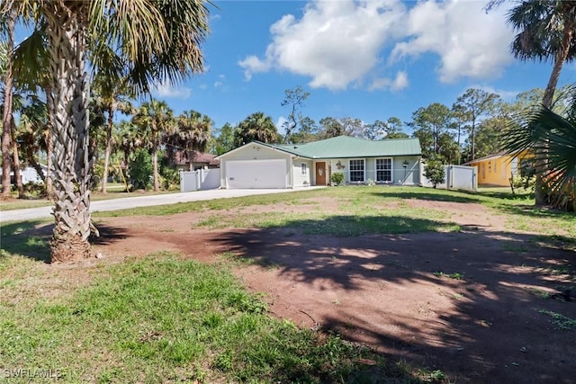 ranch-style house with a front yard, metal roof, fence, a garage, and driveway