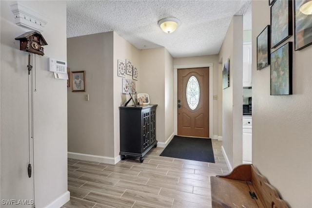 foyer entrance featuring wood tiled floor, baseboards, and a textured ceiling