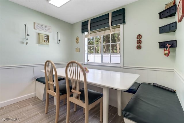 dining room featuring a wainscoted wall and wood tiled floor