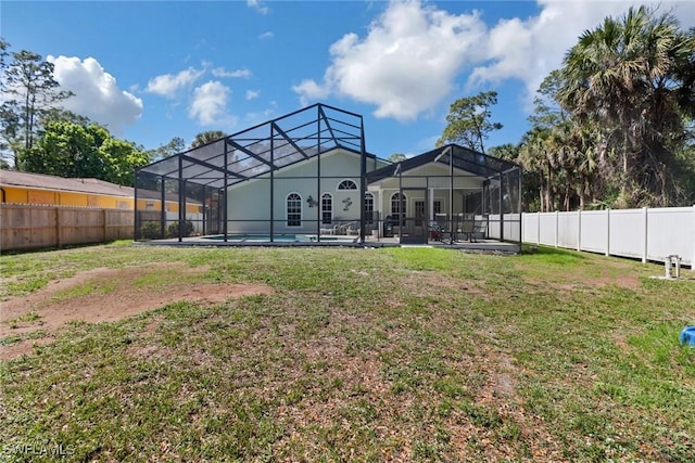 back of property with glass enclosure, a fenced backyard, and a yard