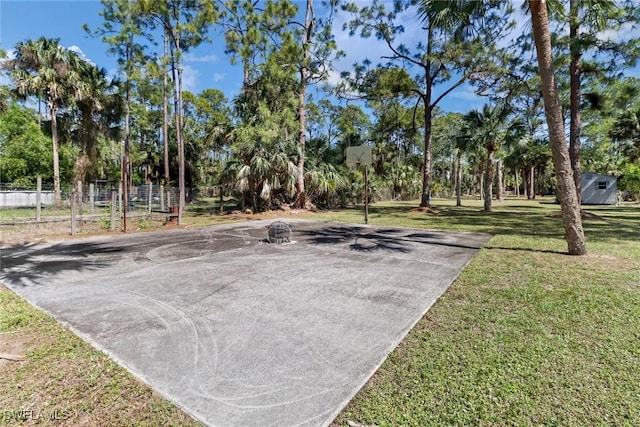 exterior space with community basketball court, a yard, and fence