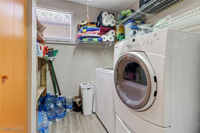 clothes washing area featuring laundry area, washing machine and dryer, and wood finish floors