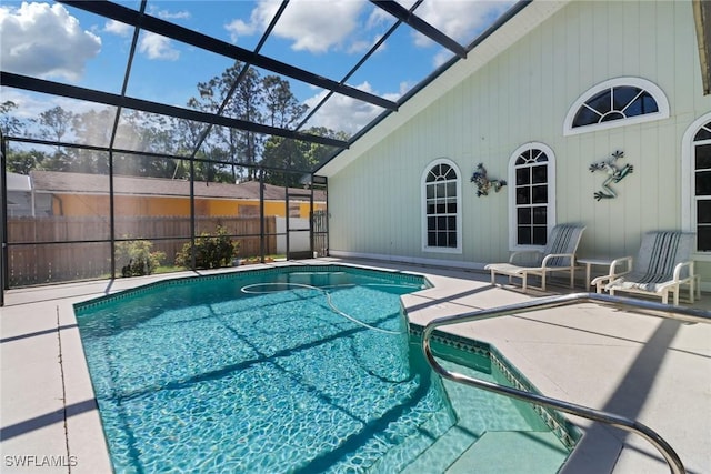 view of pool featuring glass enclosure, fence, a fenced in pool, and a patio