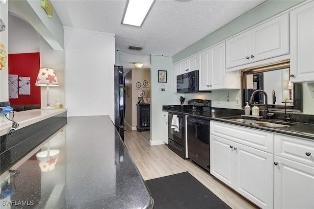 kitchen with black appliances, visible vents, white cabinets, and a sink