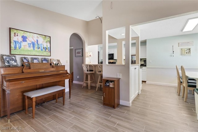 living area featuring wood tiled floor, baseboards, and arched walkways