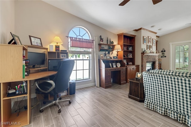 office with a wealth of natural light, lofted ceiling, a brick fireplace, and wood finish floors